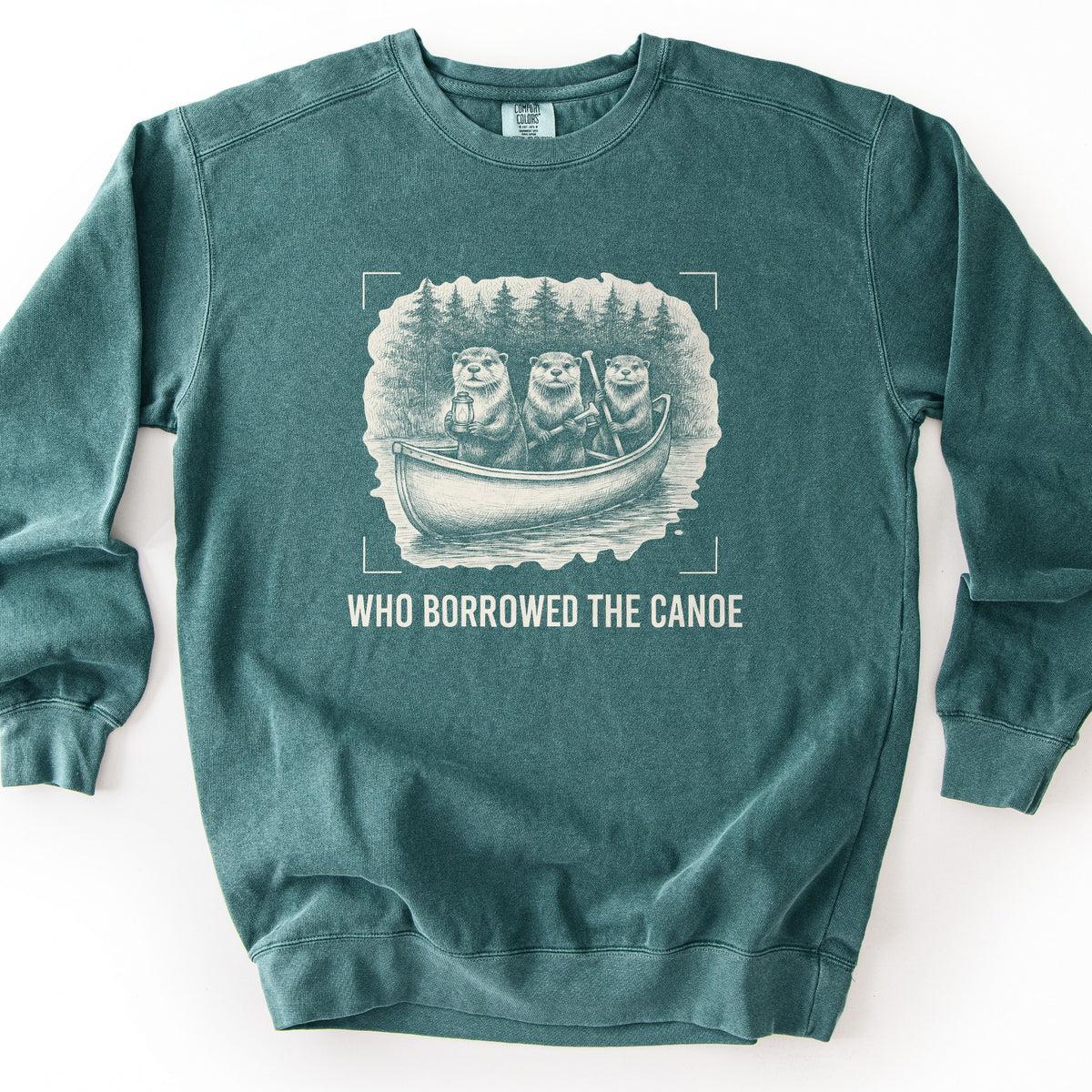 Who Borrowed The Canoe Comfort Colors crewneck sweatshirt in Blue Spruce, laid flat. A cream sketch-style print shows three otters in a canoe on a lake with pine trees behind, one holding a lantern and one a paddle, framed by corner marks above the words Who Borrowed The Canoe. Shown on a white background.