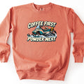 Coffee First Powder Next Comfort Colors crewneck sweatshirt in Terracotta, laid flat. A cartoon teal and white snowmobile with a helmet on the seat and a yellow thermos strapped to the back kicks up snow between the words Coffee First and Powder Next. Laid on a white background.