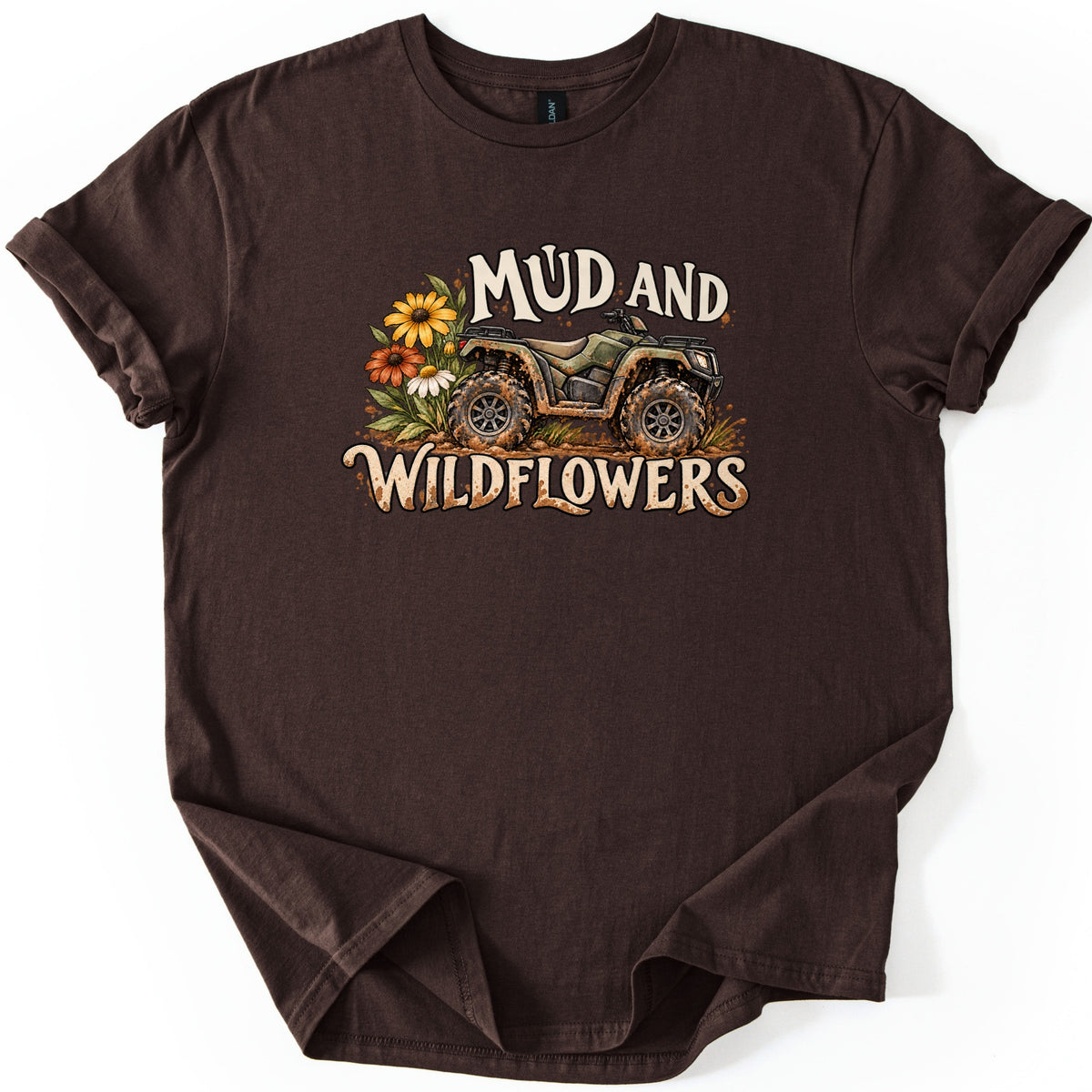 Mud and Wildflowers Comfort Colors T-shirt in Dark Chocolate, laid flat. A mud-splattered green ATV sits beside yellow, orange and white wildflowers between the words Mud and Wildflowers in cream lettering. The shirt has rolled sleeves on a white background.