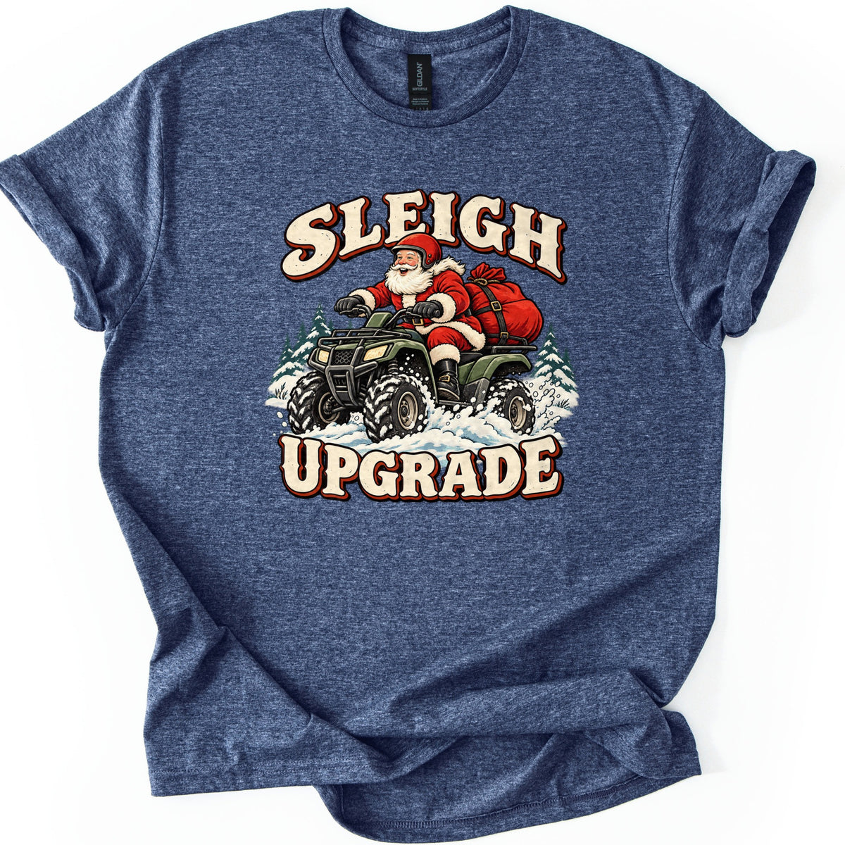 Sleigh Upgrade Comfort Colors T-shirt in Heather Navy, laid flat. Santa in a red helmet rides a green four-wheeler through snow with a red gift sack behind him, between the words Sleigh Upgrade. The shirt lies on a white background with rolled sleeves.