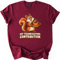 My Thanksgiving Contribution Comfort Colors T-shirt in Maroon, laid flat. A smiling cartoon squirrel holds a woven basket of acorns, a small pumpkin and autumn leaves above the words My Thanksgiving Contribution in cream letters. The shirt has cuffed sleeves on a white background.