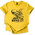 ATV Just Send It Comfort Colors T-shirt in Daisy, laid flat. A black illustration of a helmeted rider on an airborne quad ATV, one fist raised, kicking up dust above the words Just Send It in bold tire-tread letters. The shirt has cuffed sleeves on a white background.