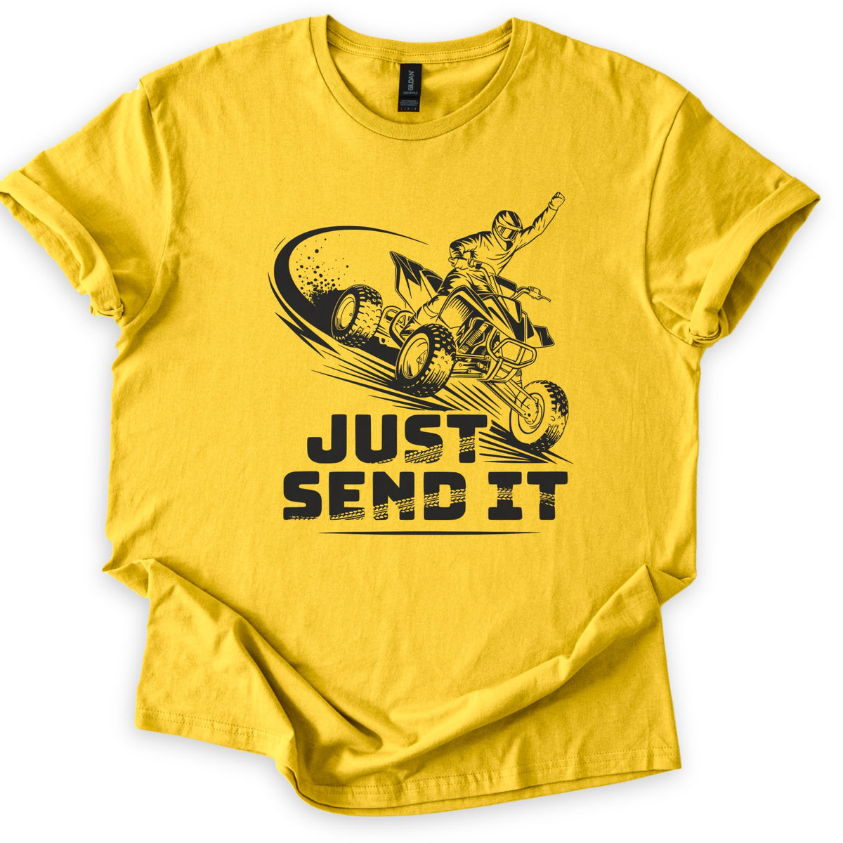 ATV Just Send It Comfort Colors T-shirt in Daisy, laid flat. A black illustration of a helmeted rider on an airborne quad ATV, one fist raised, kicking up dust above the words Just Send It in bold tire-tread letters. The shirt has cuffed sleeves on a white background.
