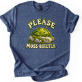 Please Moss Quietly Comfort Colors T-shirt in Heather Navy, laid flat. A sleepy, smiling mound of green moss with a tiny sprout rests on gray rocks between the words Please Moss Quietly. in cream letters edged with moss. The sleeves are rolled on a white background.