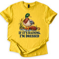 If It's Raining, I'm Dressed Comfort Colors T-shirt in Daisy, laid flat. A mallard duck with water dripping off its wing stands in a puddle by cattails next to a closed red umbrella, above the words IF IT'S RAINING, I'M DRESSED in dark green. Cuffed sleeves, white background.