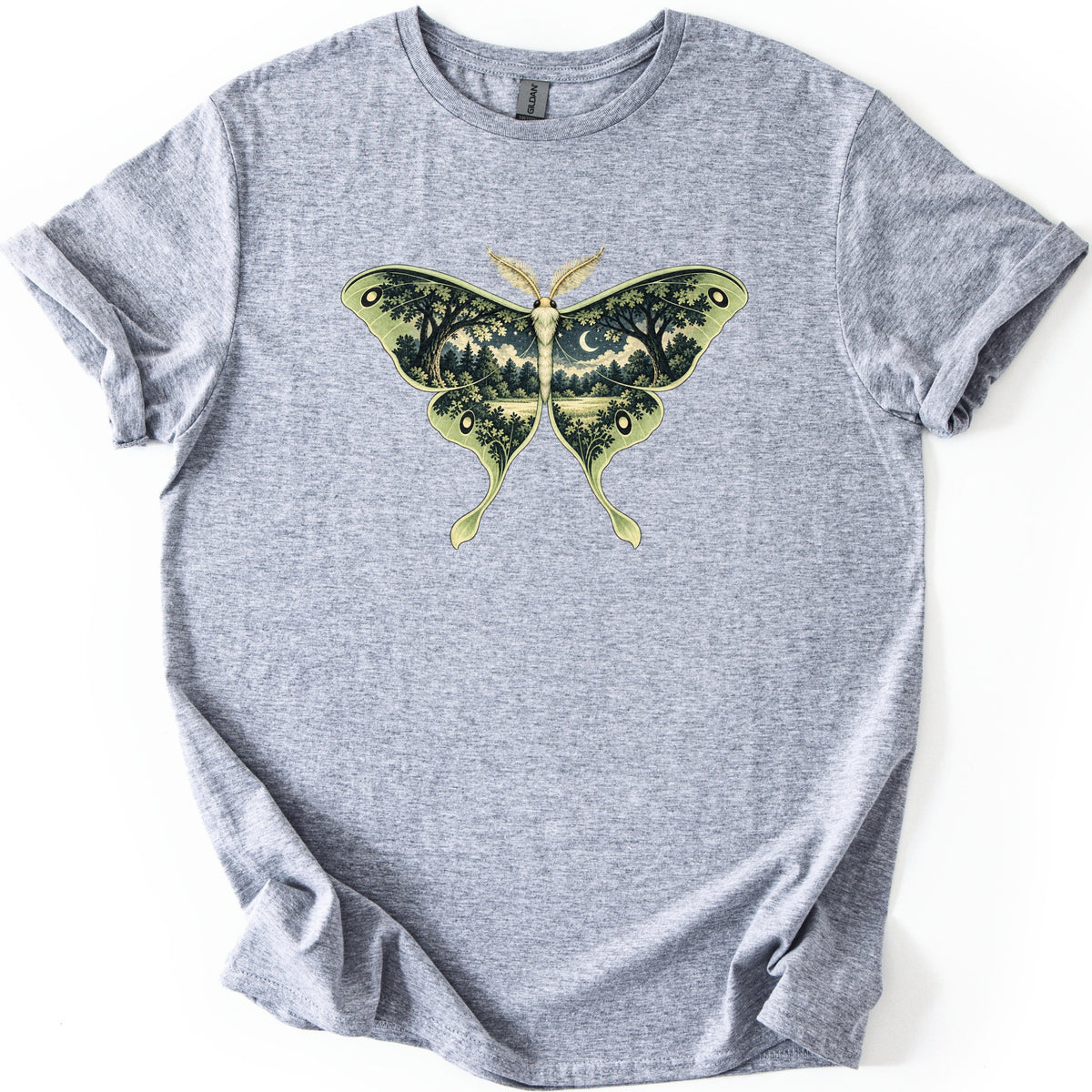 Luna Moth Night Comfort Colors T-shirt in Sport Grey, laid flat. A large green luna moth is printed on the chest, its wings filled with a night forest scene of trees, a meadow and a crescent moon. No words are printed. The shirt has rolled sleeves on a white background.