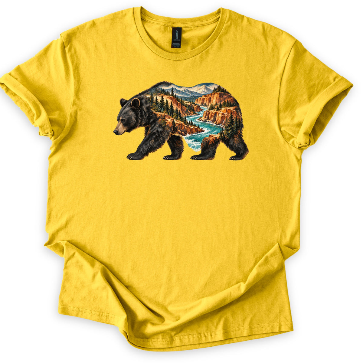 Bear River Canyon Comfort Colors T-shirt in Daisy, laid flat. A walking black bear silhouette filled with a canyon scene: a turquoise river winding between orange cliffs, pine trees, and snowy mountains. The shirt lies on a white background with sleeves rolled.