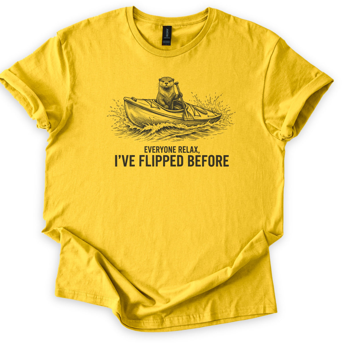 Everyone Relax I've Flipped Before Comfort Colors T-shirt in Daisy, laid flat. A black sketch-style otter paddles a kayak through splashing waves above the words Everyone Relax, I've Flipped Before. The shirt has rolled sleeves and lies on a white background.