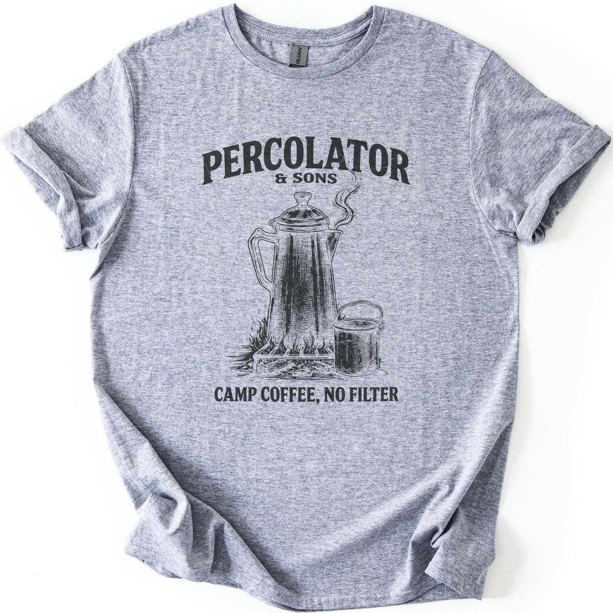 Percolator & Sons Comfort Colors T-shirt in Sport Grey, laid flat. A sketched coffee percolator steams on a grate over a campfire beside a tin cup, under the words Percolator & Sons and above Camp Coffee, No Filter, in black ink. The sleeves are rolled on a white background.