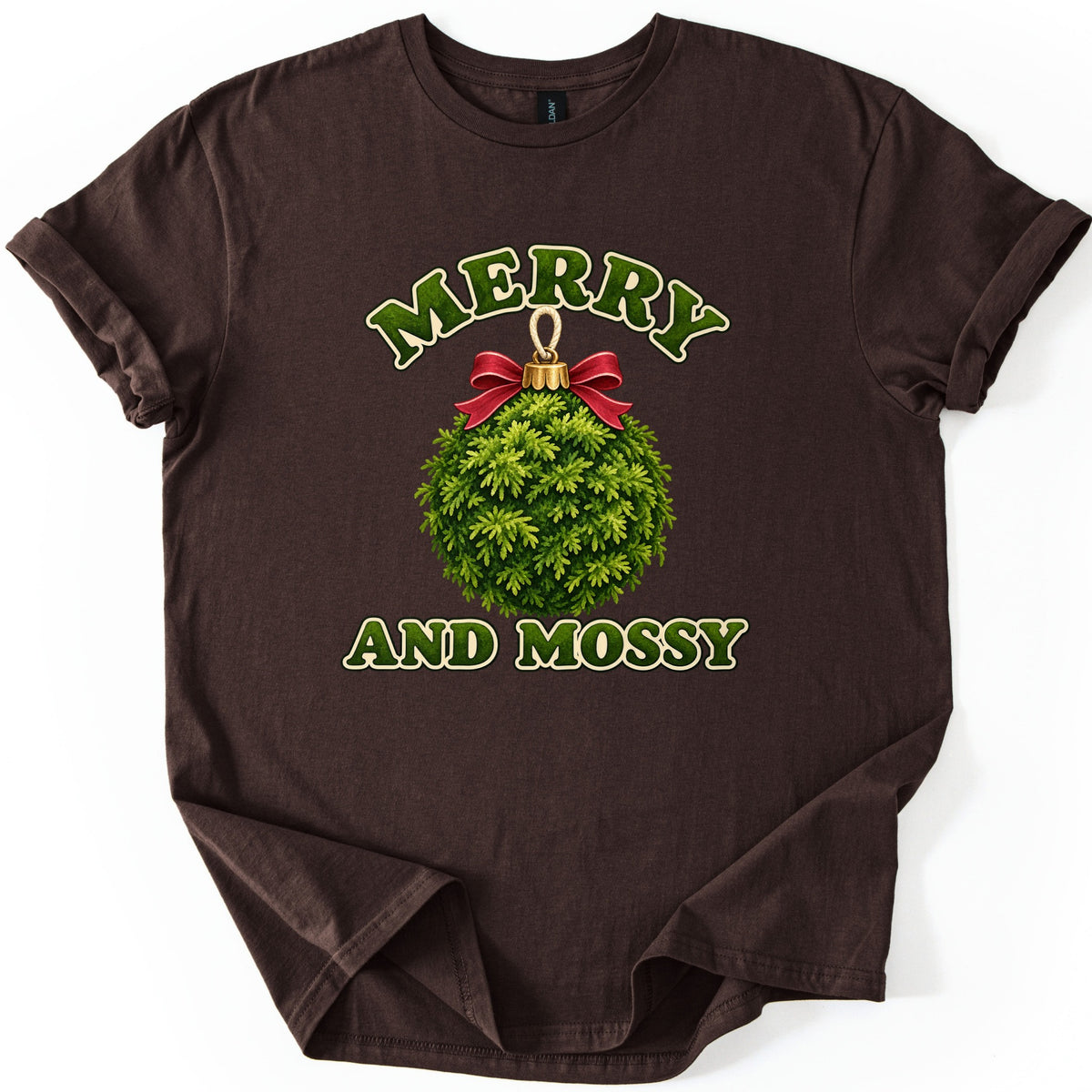 Merry and Mossy Comfort Colors T-shirt in Dark Chocolate, laid flat. A round ornament made of green moss with a red bow and gold cap sits between the words Merry and Mossy in green moss-textured letters outlined in cream. Sleeves are rolled on a white background.