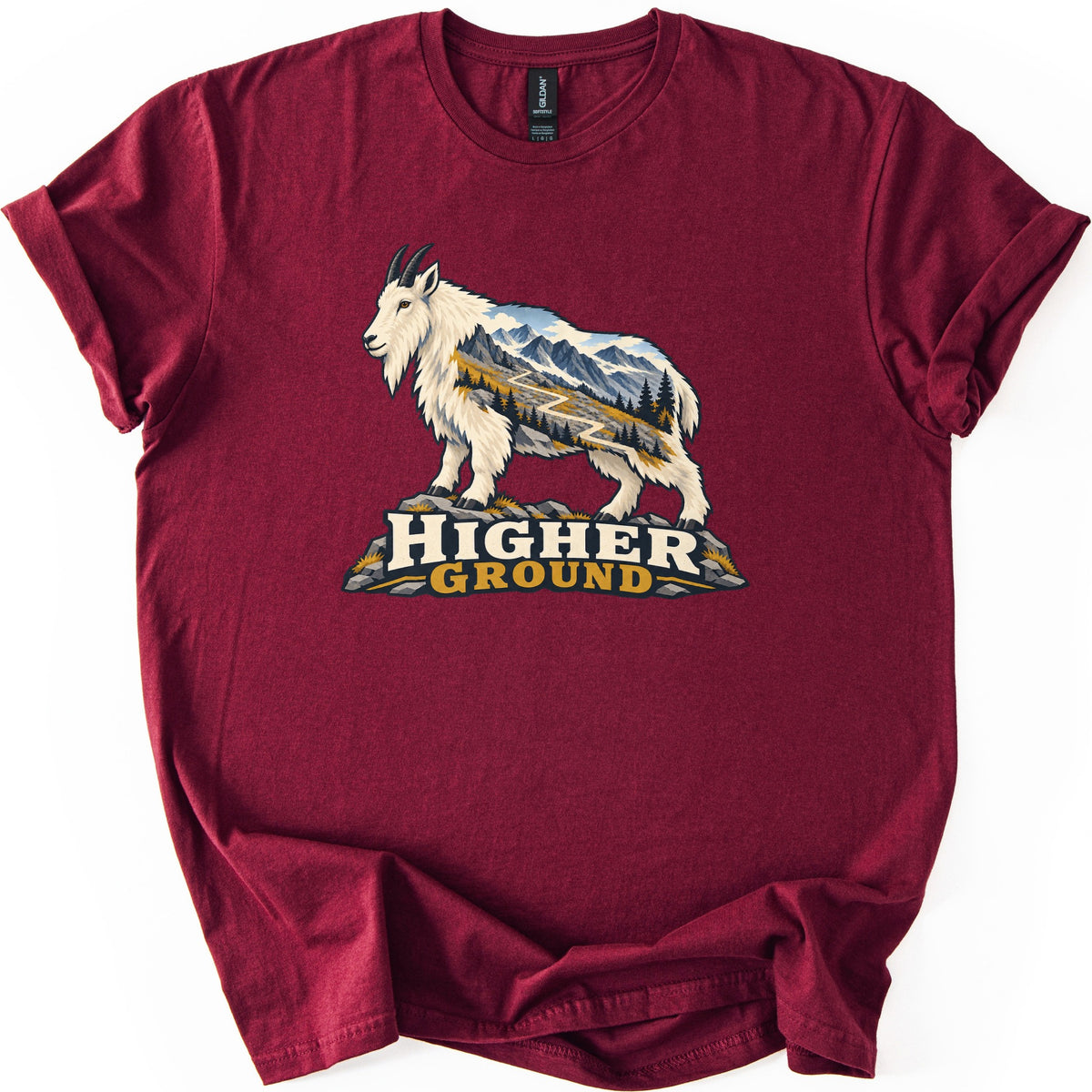 Higher Ground Comfort Colors T-shirt in Maroon, laid flat. A white mountain goat stands on gray rocks, its body filled with snowy peaks, pine trees and a winding trail, above the words Higher Ground. The sleeves are cuffed on a plain white background.