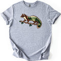 Pine Marten Forest Comfort Colors T-shirt in Sport Grey, laid flat. A brown and cream pine marten stands on a pine branch, its body and tail filled with evergreen trees, a meadow, a river and distant mountains. No words. Sleeves are cuffed on a white background.