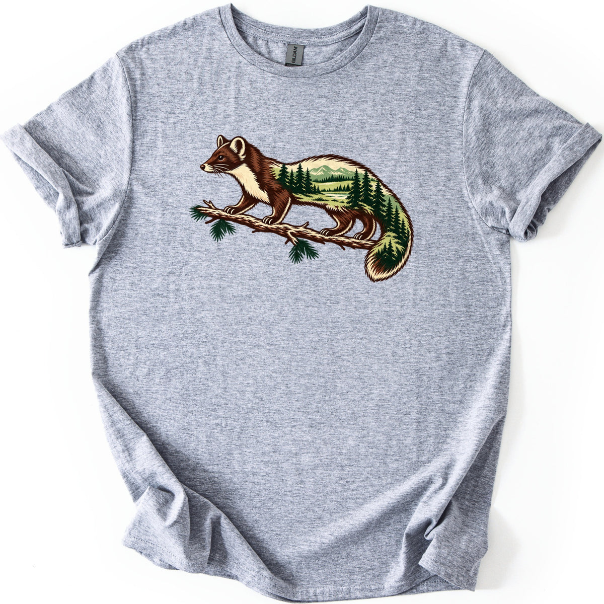 Pine Marten Forest Comfort Colors T-shirt in Sport Grey, laid flat. A brown and cream pine marten stands on a pine branch, its body and tail filled with evergreen trees, a meadow, a river and distant mountains. No words. Sleeves are cuffed on a white background.