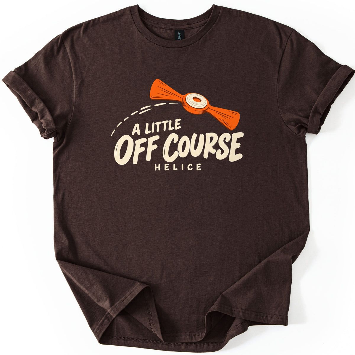 A Little Off Course Comfort Colors T-shirt in Dark Chocolate, laid flat. An orange two-winged helice target with a cream center flies along a dashed arc above cream lettering reading A Little Off Course, with Helice below. The shirt has rolled sleeves on a white background.