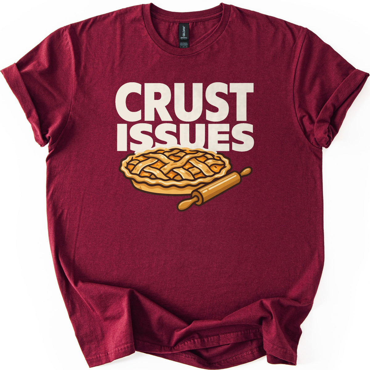 Crust Issues Comfort Colors T-shirt in Maroon, laid flat. Cream block letters read CRUST ISSUES above a cartoon lattice-top pie with a wooden rolling pin. The shirt has rolled sleeves and lies on a plain white background.
