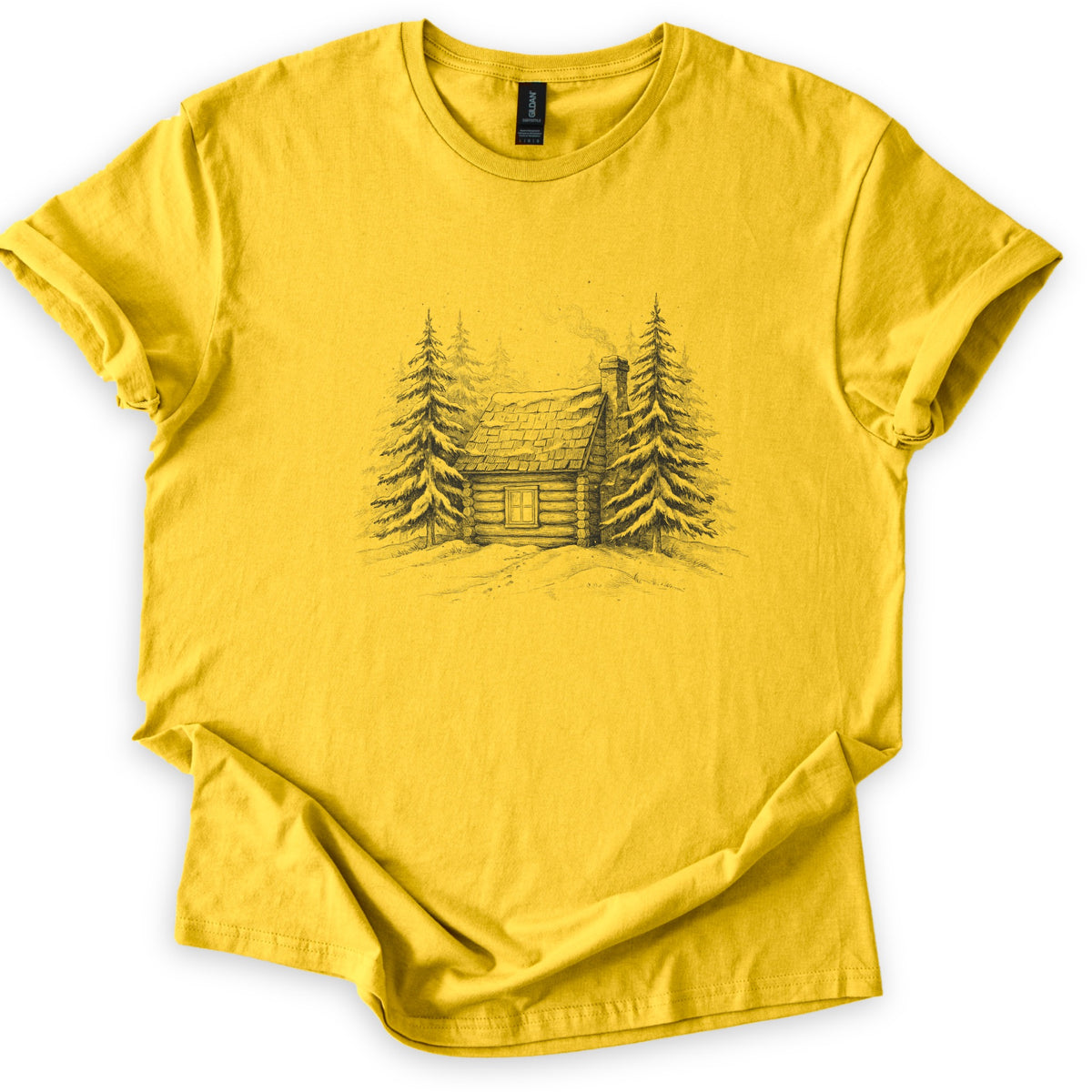 Snowy Log Cabin Comfort Colors T-shirt in Daisy, laid flat. A pencil-style sketch of a snow-covered log cabin with a smoking chimney and one window, set between snowy pine trees on a drift. No words. Sleeves are rolled on a white background.