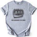Who Borrowed The Canoe Comfort Colors T-shirt in Sport Grey, laid flat. A black pencil-style sketch of three otters in a canoe before pine trees, one holding a lantern and two holding paddles, inside corner brackets above the words WHO BORROWED THE CANOE. Sleeves rolled, on white.