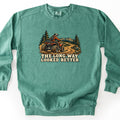 The Long Way Looked Better Comfort Colors crewneck sweatshirt in Light Green, laid flat. A rider in an orange jacket and white helmet drives a red ATV up a winding dirt trail past pine trees and mountains, above the words The Long Way Looked Better. Shown on a white background.