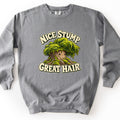 Nice Stump Great Hair Comfort Colors crewneck sweatshirt in Grey, laid flat. A cartoon tree stump with a small smiling face and a thick mop of green moss for hair sits between the words Nice Stump above and Great Hair. below, in cream bubble letters. The sweatshirt lies on a white background.