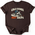 Cold Hands Hot Grips Comfort Colors T-shirt in Dark Chocolate, laid flat. A rider in a helmet and blue jacket speeds on a snowmobile through spraying snow, with small flames rising from the handlebar grips, between the words Cold Hands and Hot Grips. Sleeves cuffed, on white.