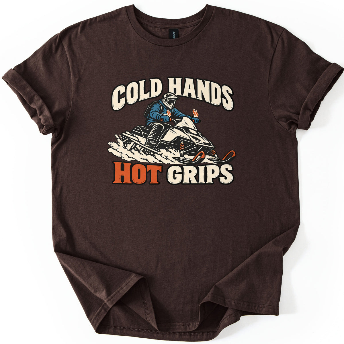 Cold Hands Hot Grips Comfort Colors T-shirt in Dark Chocolate, laid flat. A rider in a helmet and blue jacket speeds on a snowmobile through spraying snow, with small flames rising from the handlebar grips, between the words Cold Hands and Hot Grips. Sleeves cuffed, on white.