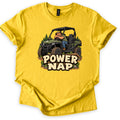 Power Nap Comfort Colors T-shirt in Daisy, laid flat. A cartoon man in a cap sleeps slumped over the wheel of a green side-by-side UTV among pine trees, above the words Power Nap in cream letters. The shirt lies on a white background with sleeves cuffed.