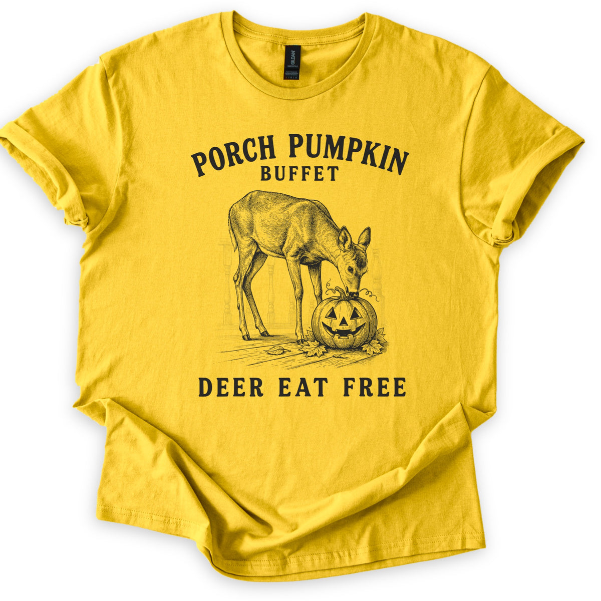 Porch Pumpkin Buffet Comfort Colors T-shirt in Daisy, laid flat. A black engraving-style drawing of a deer nibbling a carved jack-o'-lantern on a porch with fallen leaves, between the words Porch Pumpkin Buffet and Deer Eat Free. Sleeves are rolled, on a white background.