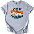 Cap Collector Comfort Colors T-shirt in Sport Grey, laid flat. An orange propeller-shaped tool sits behind three white ringed discs between the words Cap Collector in dark green brush letters, with Helice below. Sleeves are rolled on a white background.