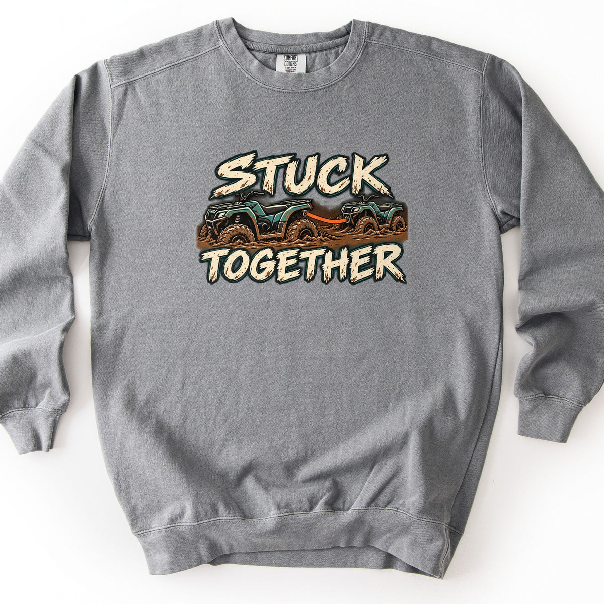 Stuck Together Comfort Colors crewneck sweatshirt in Grey, laid flat. Two teal ATVs covered in mud, one towing the other with an orange strap, between the words Stuck Together in cream distressed lettering. Shown on a white background.