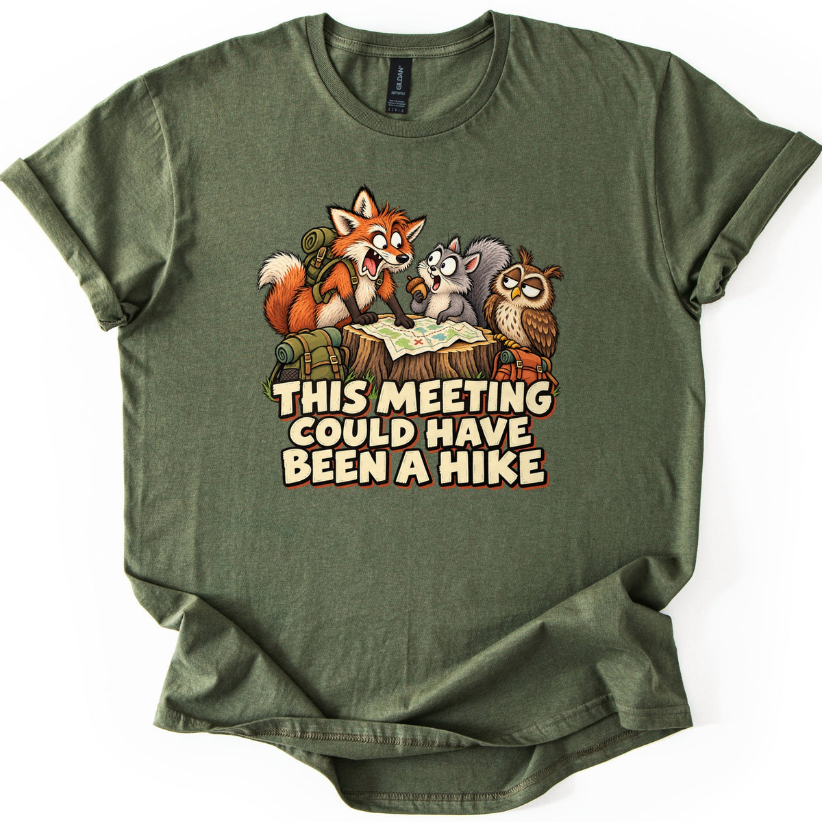 This Meeting Could Have Been a Hike Comfort Colors T-shirt in Military Green, laid flat. A cartoon fox, squirrel and owl with backpacks gather around a trail map on a tree stump above the words This Meeting Could Have Been a Hike. The shirt has rolled sleeves on a white background.