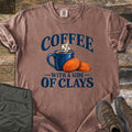 Coffee with a Side of Clays Comfort Colors T-shirt in Espresso, laid flat. A steaming blue mug of coffee beside two orange clay targets, with the words Coffee with a Side of Clays in navy. Sleeves rolled, on rustic wood with folded green pants and brown hiking boots.
