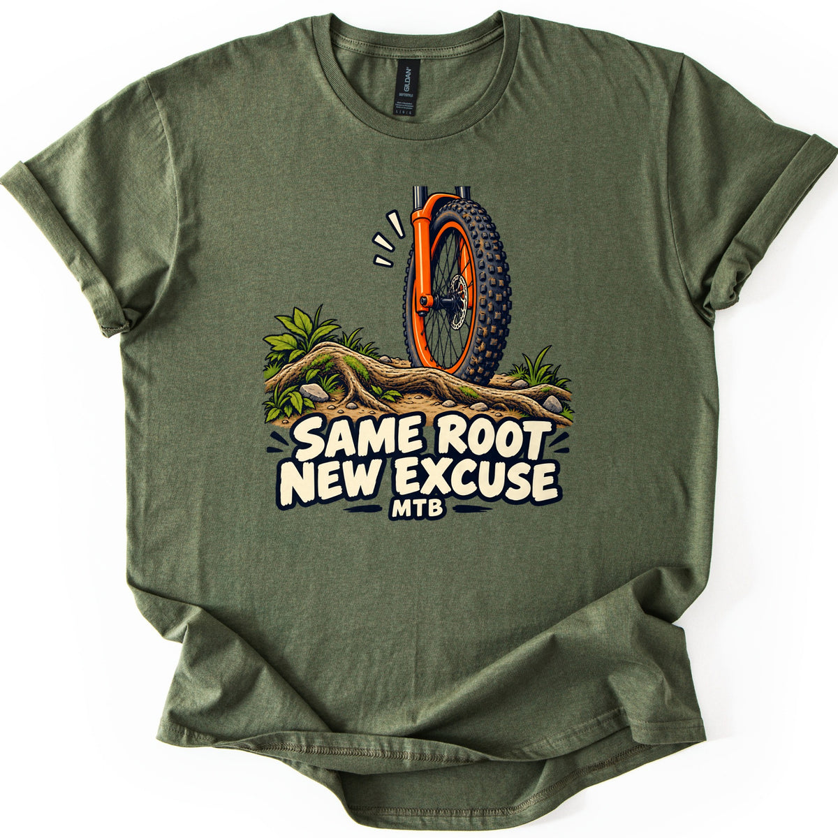 Same Root New Excuse Comfort Colors T-shirt in Military Green, laid flat. A cartoon mountain bike front wheel with an orange fork and knobby tire hits a tree root on a dirt trail with plants and rocks, above the words Same Root New Excuse MTB. Sleeves are cuffed on a white background.