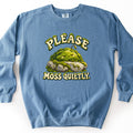 Please Moss Quietly Comfort Colors crewneck sweatshirt in Blue Jean, laid flat. A cartoon moss mound with closed eyes, a soft smile, and a small sprout sleeps on a gray rock, between the moss-covered words Please above and Moss Quietly. below. Laid on a white surface.