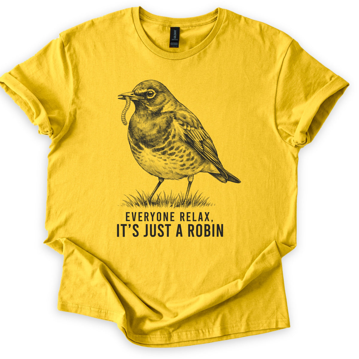 Everyone Relax It's Just A Robin Comfort Colors T-shirt in Daisy, laid flat. A black sketch-style drawing of a robin holding a worm in its beak, standing on a tuft of grass, above the words Everyone Relax, It's Just A Robin. The sleeves are rolled on a white background.