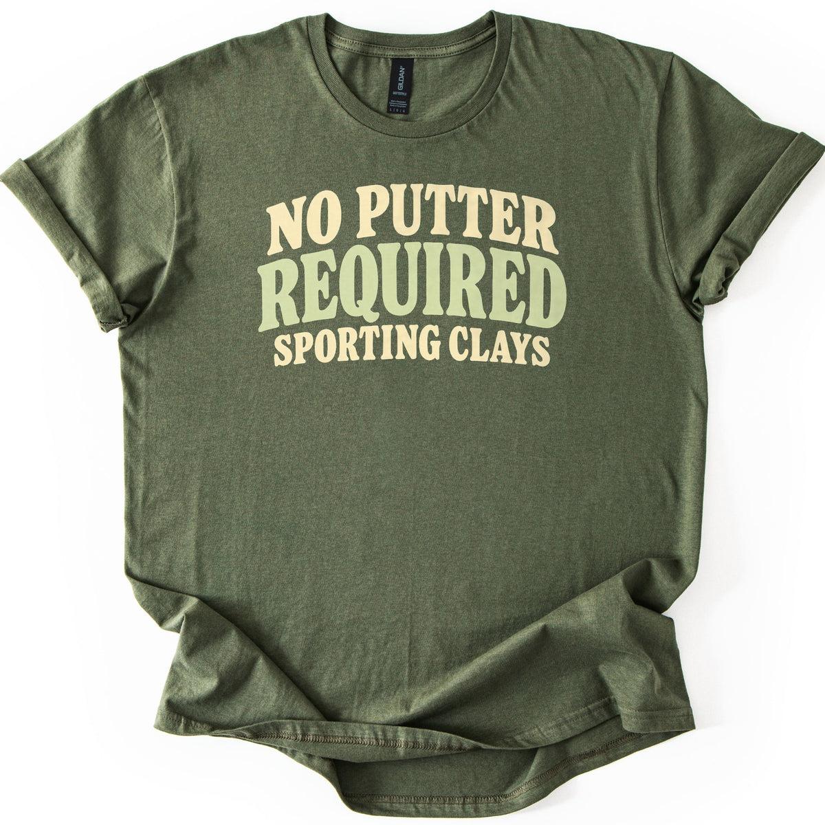 No Putter Required Comfort Colors T-shirt in Military Green, laid flat. Wavy retro letters read NO PUTTER in cream, REQUIRED in larger sage green, and SPORTING CLAYS in cream below. The shirt lies on a white background with its sleeves rolled.