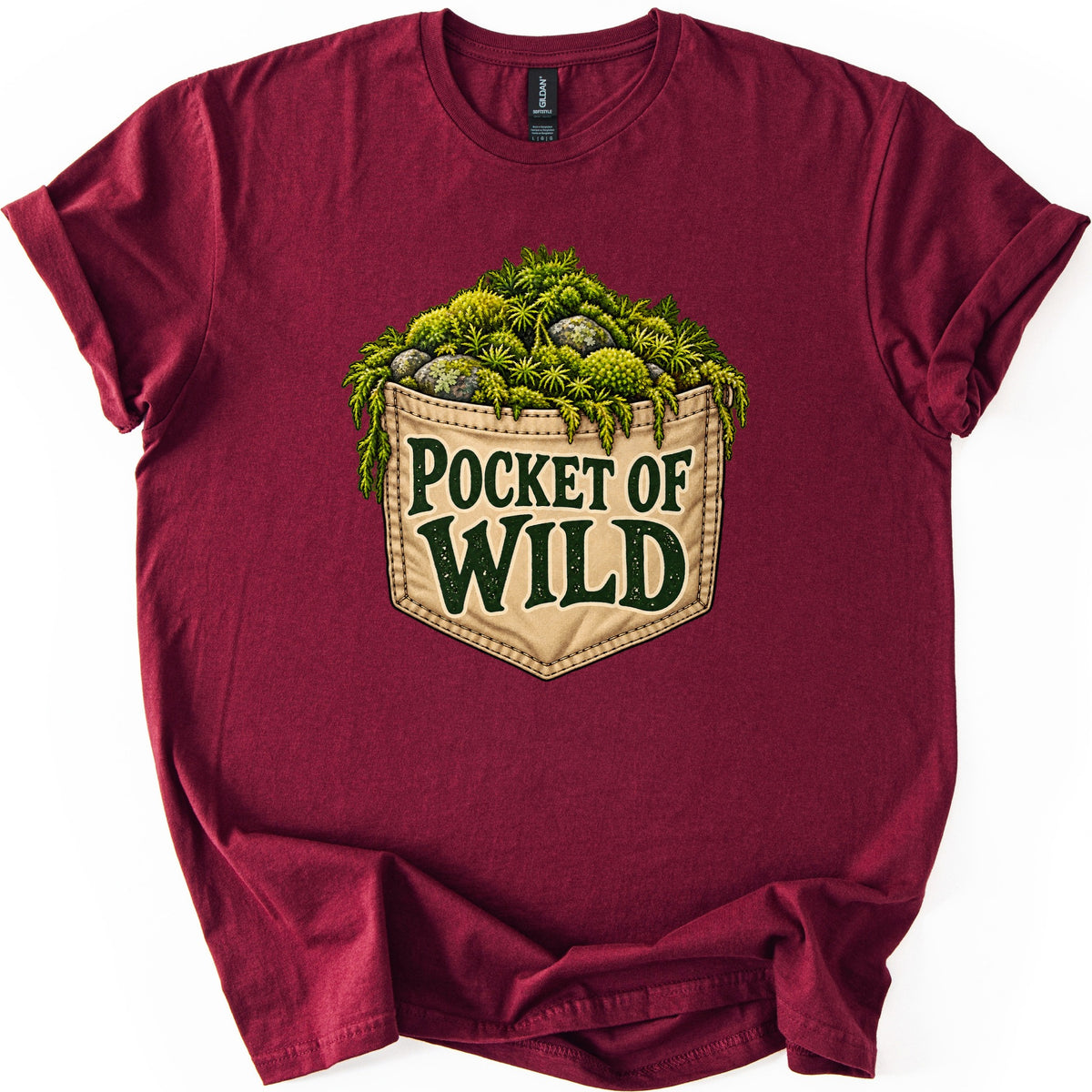 Pocket of Wild Comfort Colors T-shirt in Maroon, laid flat. A tan stitched pocket overflows with green moss, ferns and lichen-covered stones, with the words Pocket of Wild in dark green on the pocket. The shirt lies on a white background with cuffed sleeves.