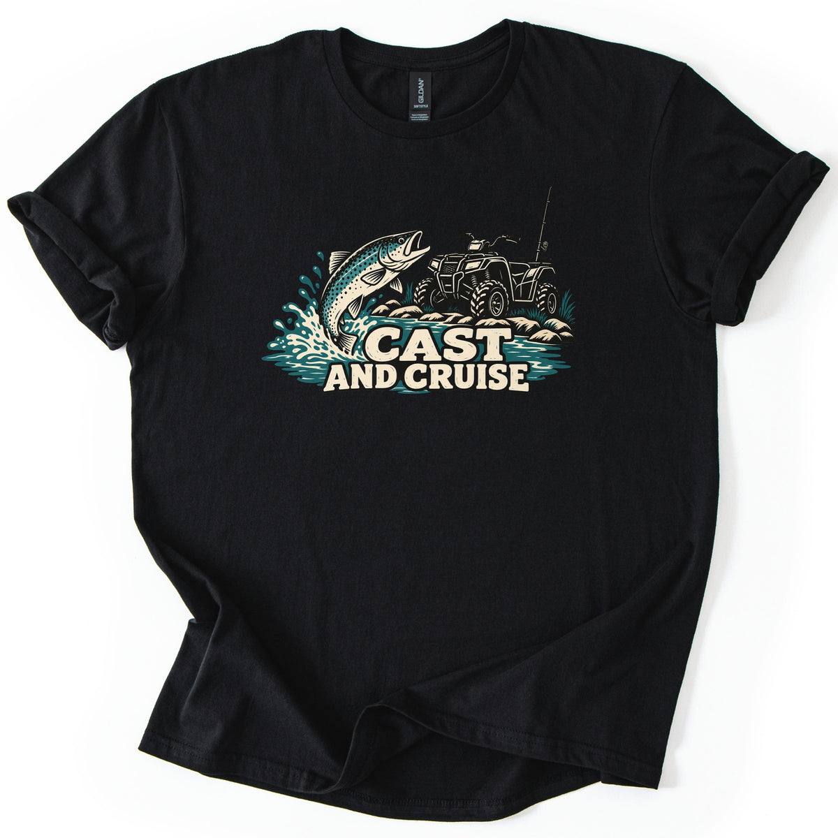 Cast and Cruise Comfort Colors T-shirt in Black, laid flat. A trout leaps from splashing teal water beside a four-wheeler ATV with a fishing rod on rocky ground, above the words Cast and Cruise. The shirt has rolled sleeves on a white background.
