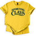 Sporting Clays Comfort Colors T-shirt in Daisy, laid flat. Dark green vintage-style lettering reads Sporting Clays, with a curling swash flowing beneath the word Clays. The shirt has rolled sleeves and lies on a plain white background.