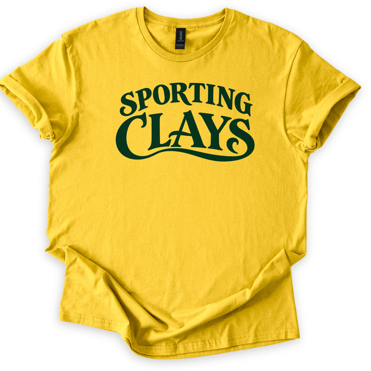Sporting Clays Comfort Colors T-shirt in Daisy, laid flat. Dark green vintage-style lettering reads Sporting Clays, with a curling swash flowing beneath the word Clays. The shirt has rolled sleeves and lies on a plain white background.