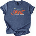 Skeet League Night Comfort Colors T-shirt in Heather Navy, laid flat. Two cream clay targets with crossing teal trails fly above the word Skeet in orange script, with League Night in cream capitals below. The shirt has rolled sleeves on a white background.