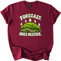 Forecast Moss Weather Comfort Colors T-shirt in Maroon, laid flat. Cream bubble letters read FORECAST: above white raindrops falling on a mound of bright green moss over gray rocks, with MOSS WEATHER. below. The shirt has rolled sleeves on a white background.