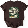 One More Bend Comfort Colors T-shirt in Dark Chocolate, laid flat. A woodcut-style print of a winding river through pine forest and mountains, with a yellow canoe in front and another far upstream, and the words Just One More Bend across the water. Sleeves rolled, on white.