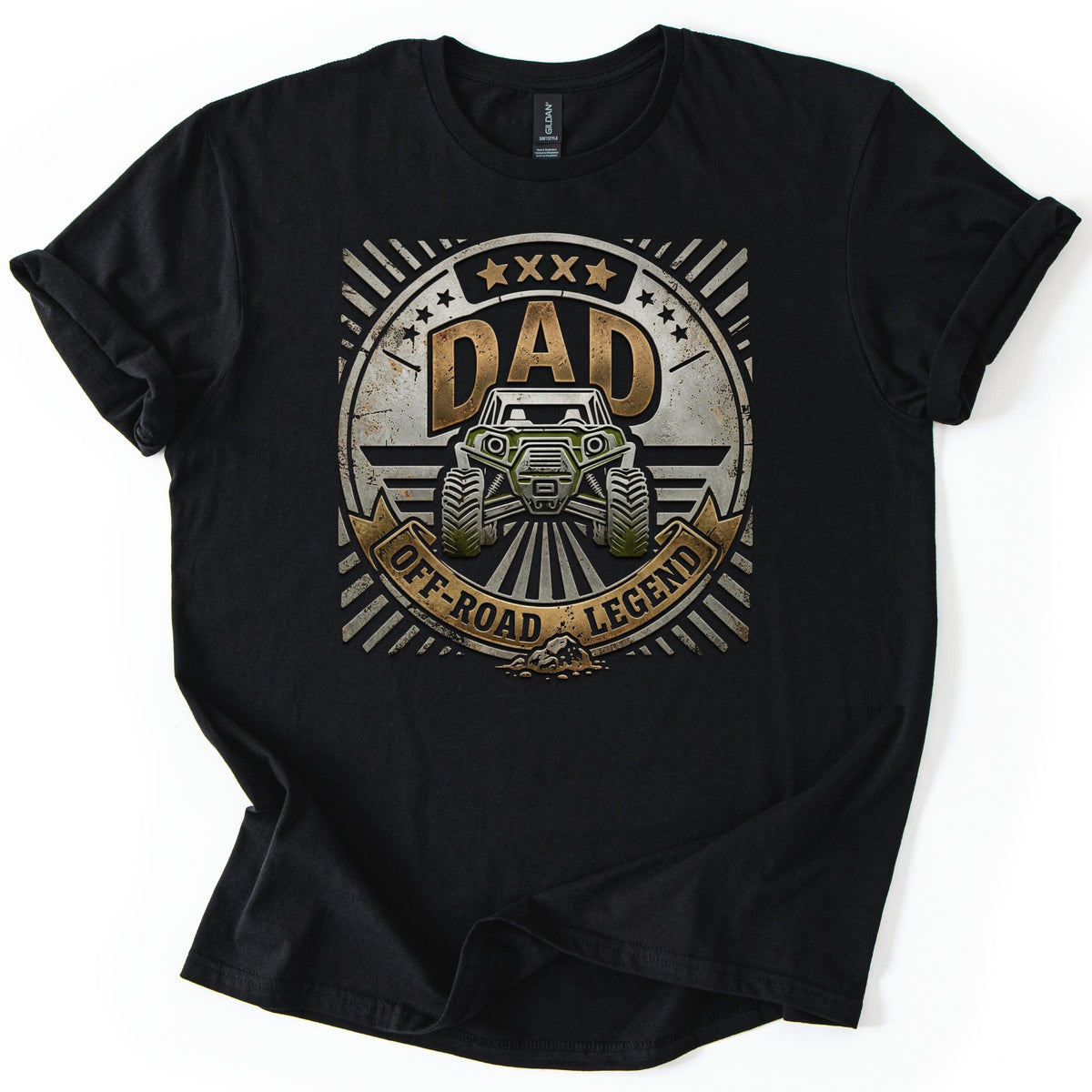 Dad Off Road Legend Comfort Colors T-shirt in Black, laid flat. A weathered metal-look badge with stars shows a green off-road side-by-side buggy below the word DAD, over a banner reading OFF-ROAD LEGEND. The shirt lies on a white surface with sleeves rolled.
