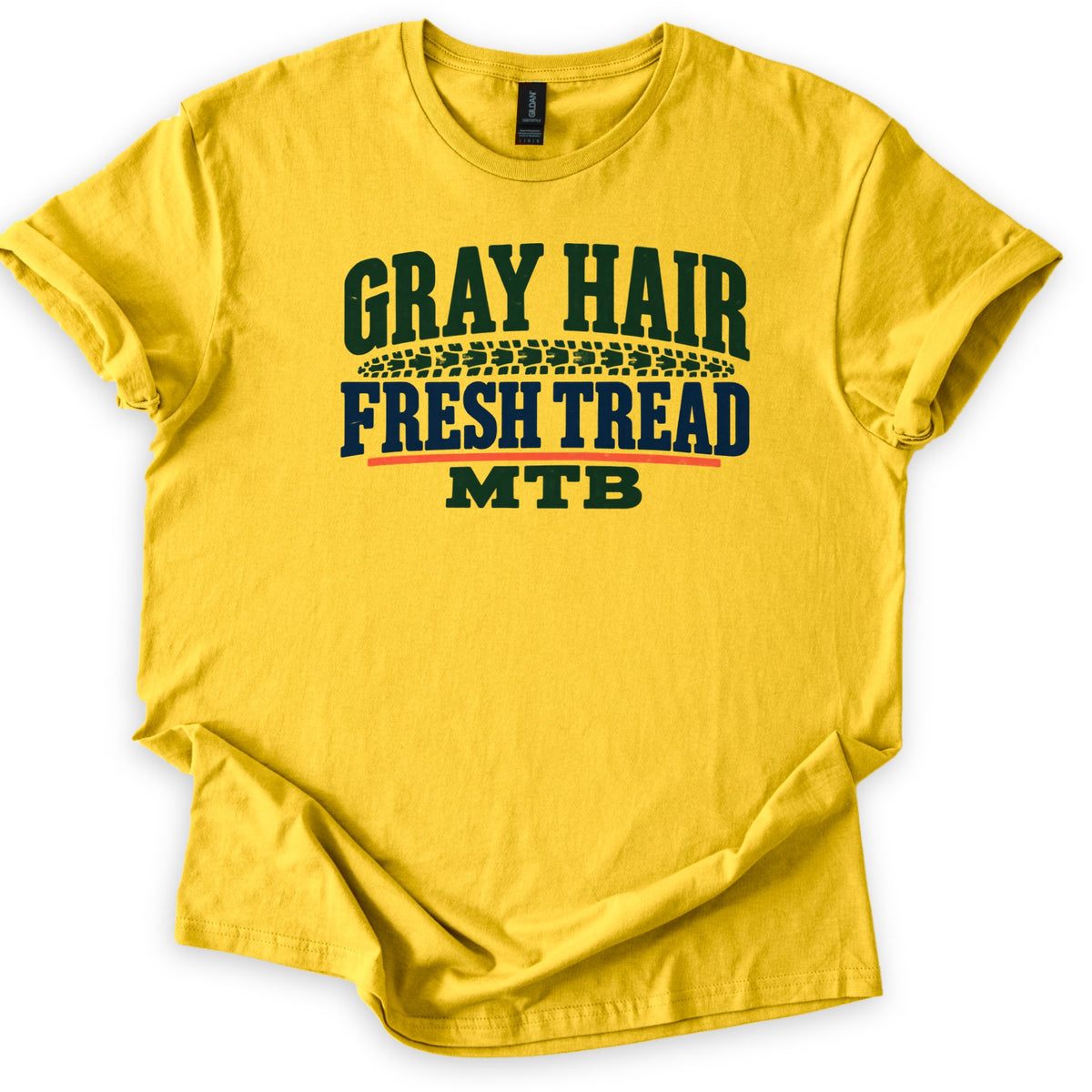 Gray Hair Fresh Tread Comfort Colors T-shirt in Daisy, laid flat. The words Gray Hair in arched dark green letters sit above a tire tread mark, then Fresh Tread in navy, an orange line, and MTB in green. Sleeves are cuffed on a white background.