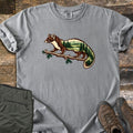 Pine Marten Forest Comfort Colors T-shirt in Grey, laid flat. A pine marten stands on a pine branch, its body filled with a scene of evergreen trees, a lake and mountains. No words are printed. Shown on weathered wood with folded olive pants and brown hiking boots.