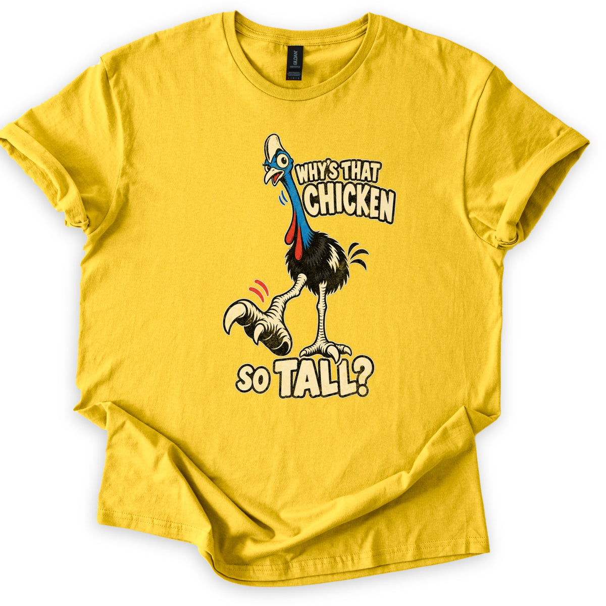 Why's That Chicken So Tall Comfort Colors T-shirt in Daisy, laid flat. A cartoon cassowary with a blue neck, red wattles and one big clawed foot raised stands beside cream words reading Why's That Chicken So Tall? The shirt lies on white with rolled sleeves.