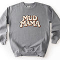 Mud Mama Comfort Colors crewneck sweatshirt in Grey, laid flat. The words Mud Mama are printed across the chest in large bubbly retro letters, cream with a black outline and a rust orange drop shadow. The sweatshirt lies on a plain white surface.