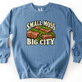 Small Moss Big City Comfort Colors crewneck sweatshirt in Blue Jean, laid flat. Front print shows red bricks with bright green moss growing between them, framed by cream arched lettering reading Small Moss above and Big City below. Shown on a white background.