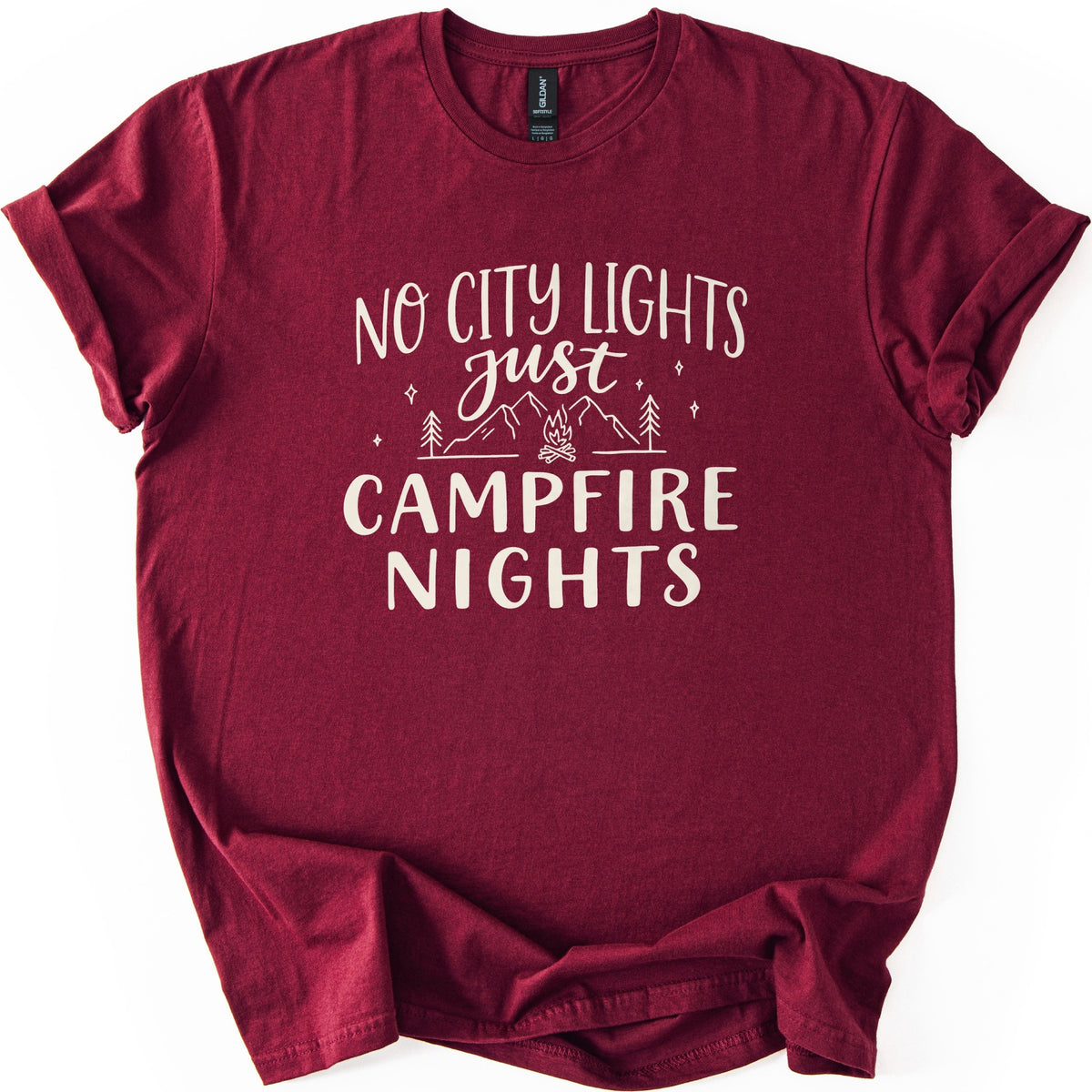 Campfire Nights Comfort Colors T-shirt in Maroon, laid flat. Cream print reads No City Lights just Campfire Nights, with a line drawing of mountains, pine trees, stars and a small campfire. The sleeves are rolled and the shirt lies on a white background.