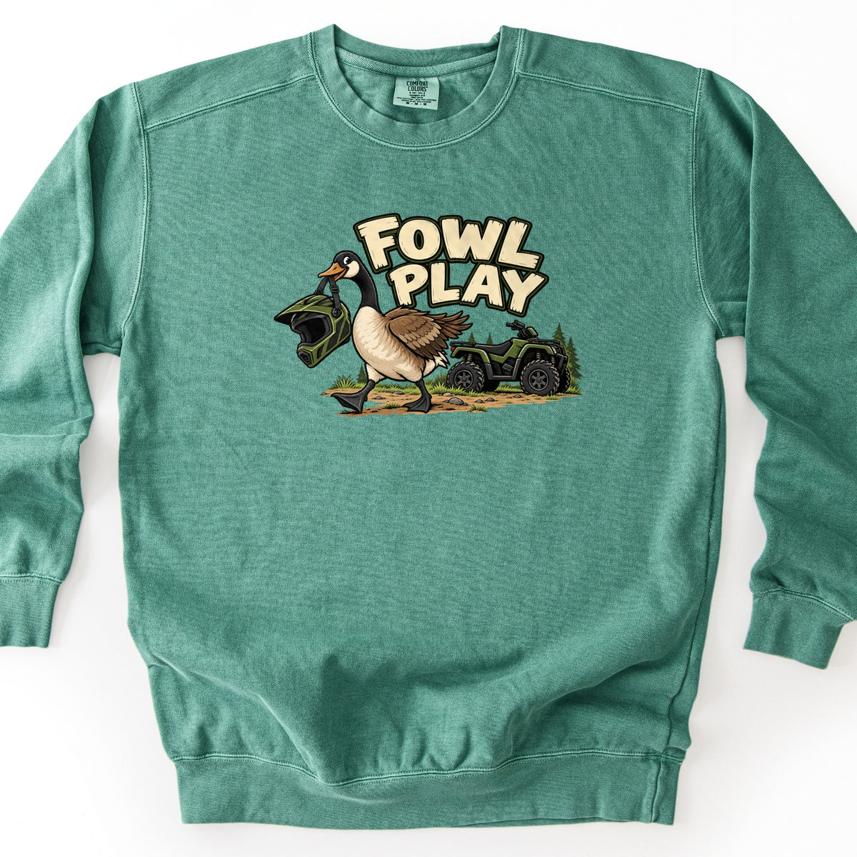 Fowl Play Comfort Colors crewneck sweatshirt in Light Green, laid flat. A cartoon Canada goose carries a green motocross helmet in its beak past a green four-wheeler and pine trees, under the words FOWL PLAY in cream letters. The sweatshirt lies on a white background.